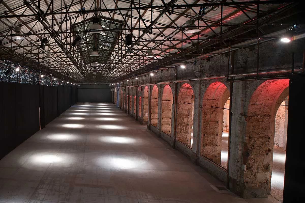 La navata vuota della Stazione Leopolda, con gli archi in mattoni illuminati di rosso